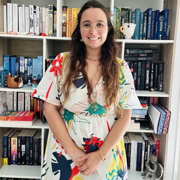 Analia Moreno, fondatrice des Pauses Littéraires, pose devant sa bibliothèque.