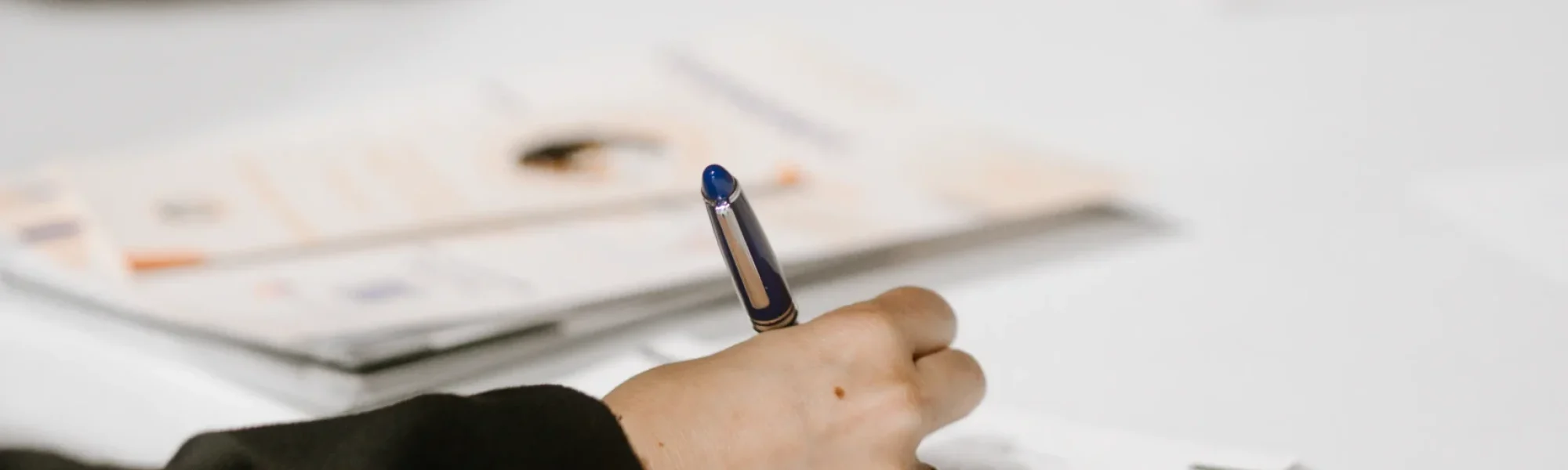 Une femme écrit sur une feuille blanche quelques lignes d'un texte pendant un atelier d'écriture ou généalogie